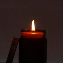 Scented candle glowing at night with soft ambient light and warm flame.